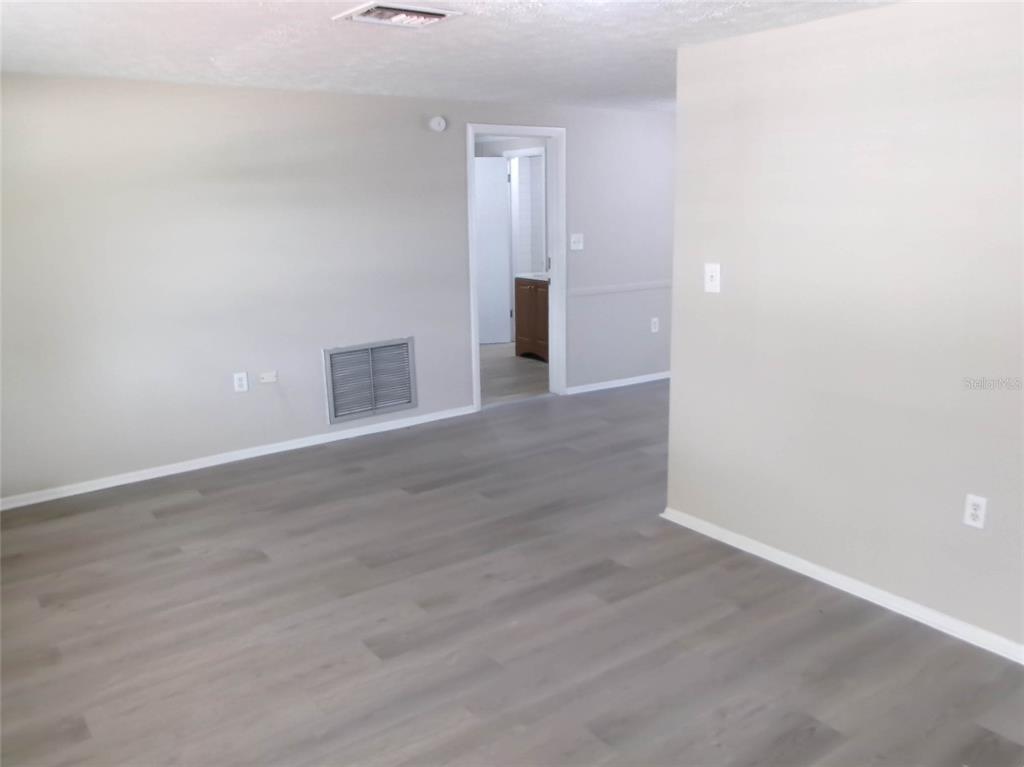 An interior view of a room with gray walls, light wood-look flooring, and a doorway — 1421 NORMANDY BOULEVARD, HOLIDAY, FL