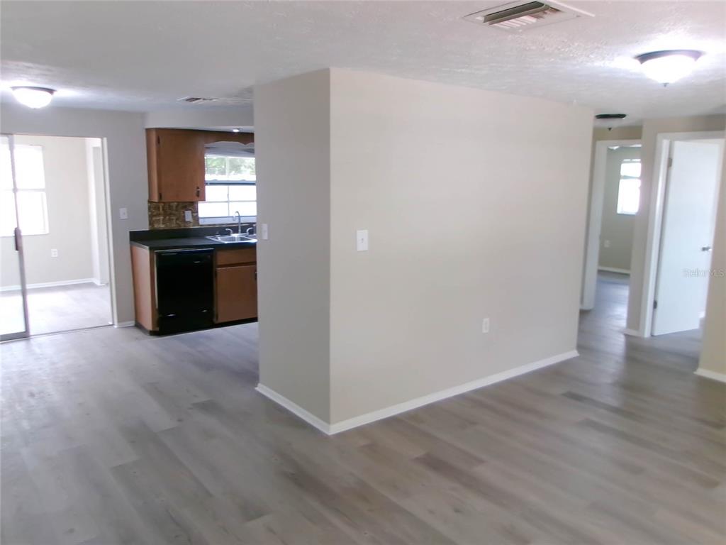 An interior view shows a kitchen with dark cabinets and appliances adjacent to a living area — 1421 NORMANDY BOULEVARD, HOLIDAY, FL