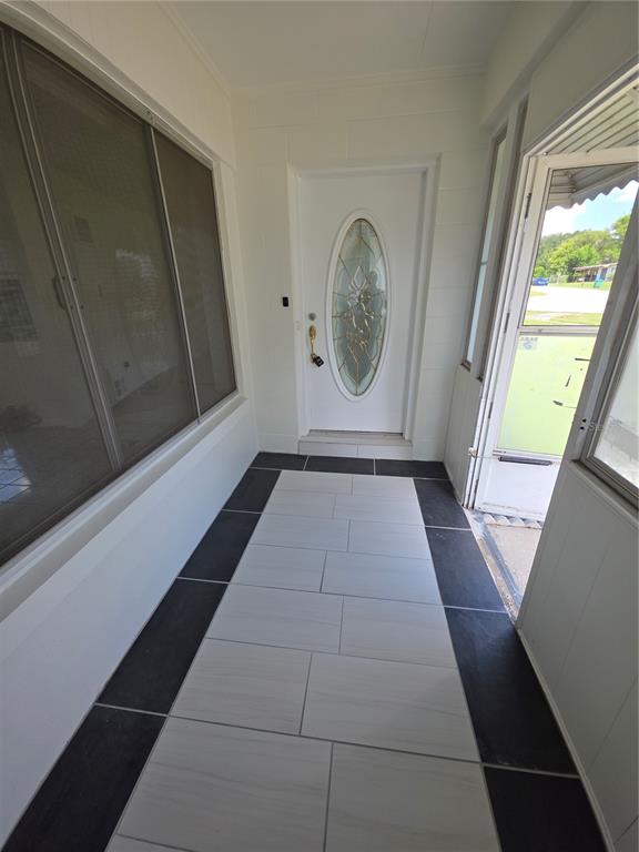 A covered entryway features a white door with an oval glass insert and tiled flooring — 802 CRAWFORD STREET, DELTONA, FL