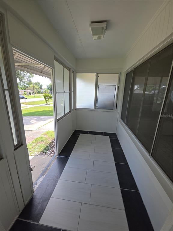 A sunroom features black and white tiled flooring, large windows, and a door leading outside — 802 CRAWFORD STREET, DELTONA, FL