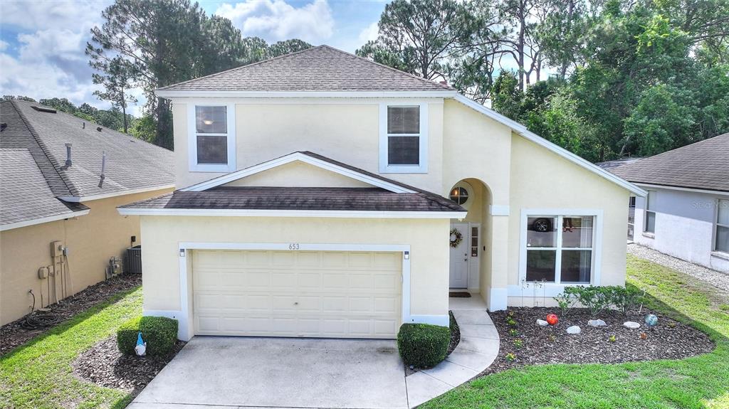 A two-story, light yellow house with a two-car garage and a front walkway — 653 JAYBEE AVENUE, DAVENPORT, FL