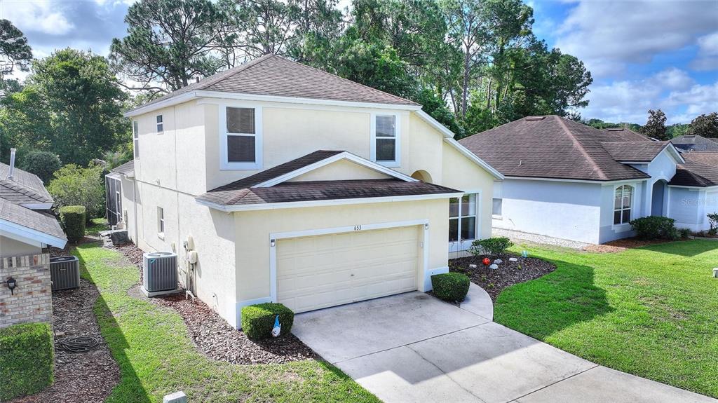 An exterior view of a two-story beige house with a garage and a shingled roof — 653 JAYBEE AVENUE, DAVENPORT, FL