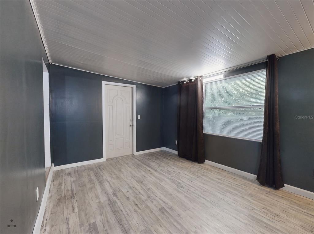 An empty room features dark gray walls, a white paneled ceiling, and light wood-look flooring — 221 EVERGREEN TERRACE, DELAND, FL