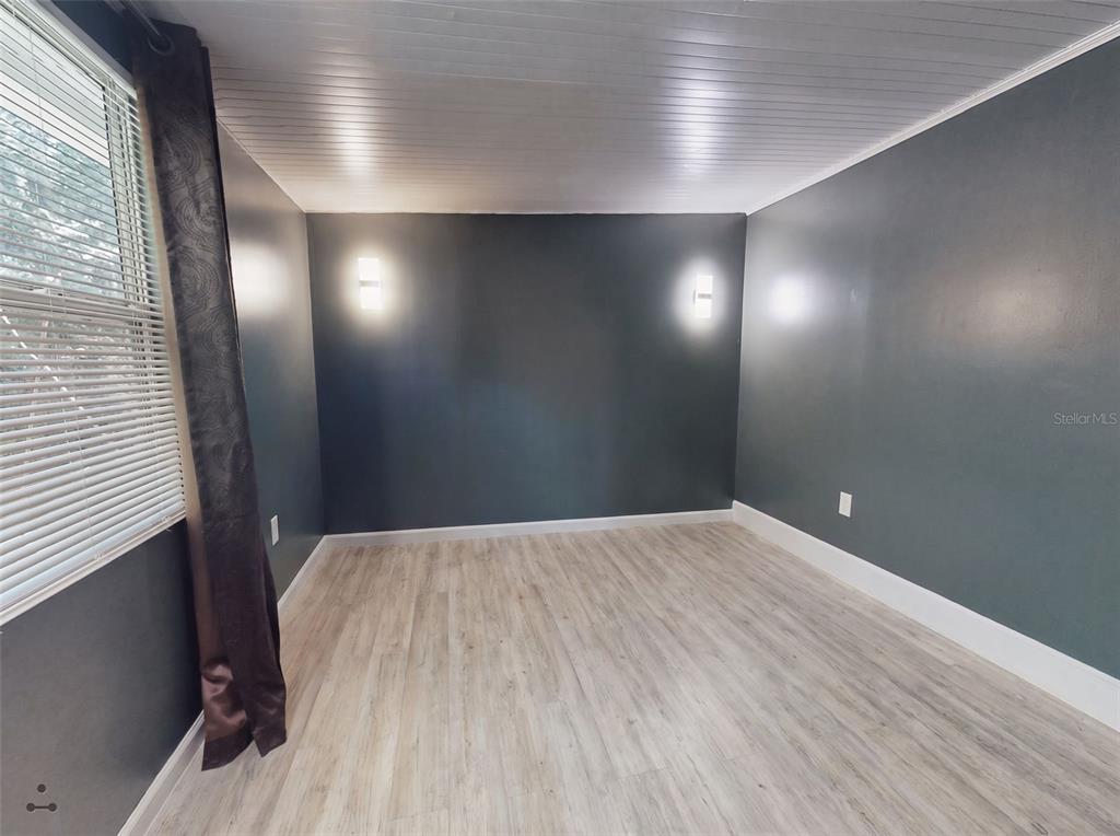 An empty room features dark gray walls, light wood-look flooring, and two wall-mounted light fixtures — 221 EVERGREEN TERRACE, DELAND, FL