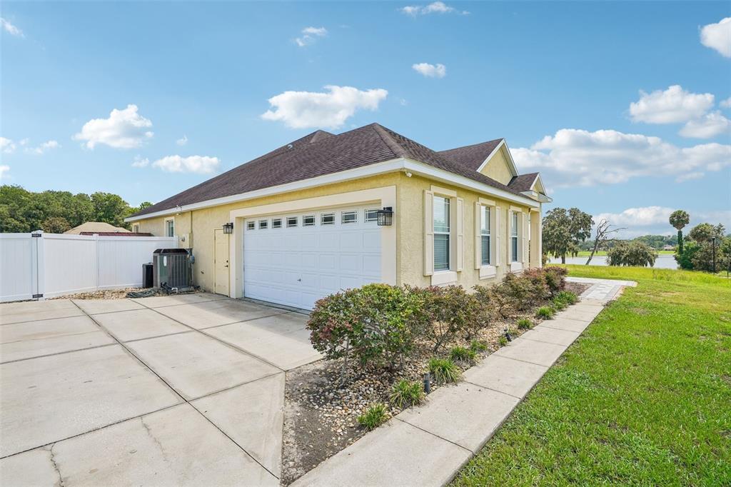 A yellow house with a white garage door, concrete driveway, and a white fence — 1113 MYRTLE BREEZES CT, FRUITLAND PARK, FL