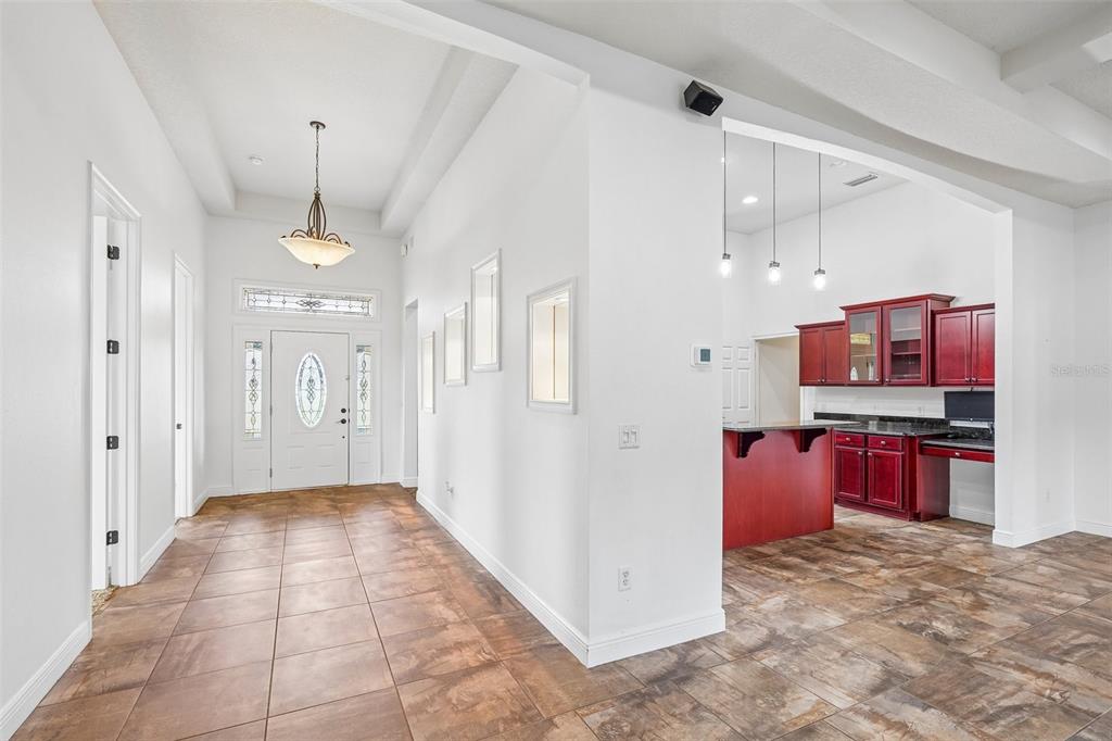 An entryway with tile flooring leads to a kitchen featuring dark wood cabinetry and counters — 1113 MYRTLE BREEZES CT, FRUITLAND PARK, FL