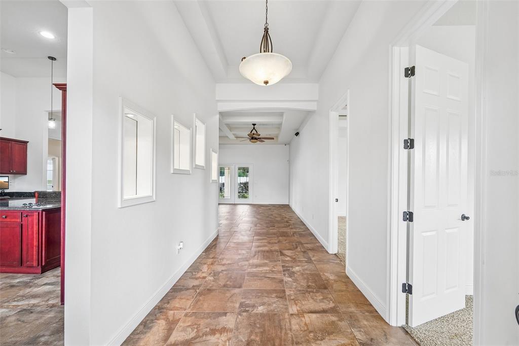 A hallway with tile flooring leads to a living area with a ceiling fan — 1113 MYRTLE BREEZES CT, FRUITLAND PARK, FL