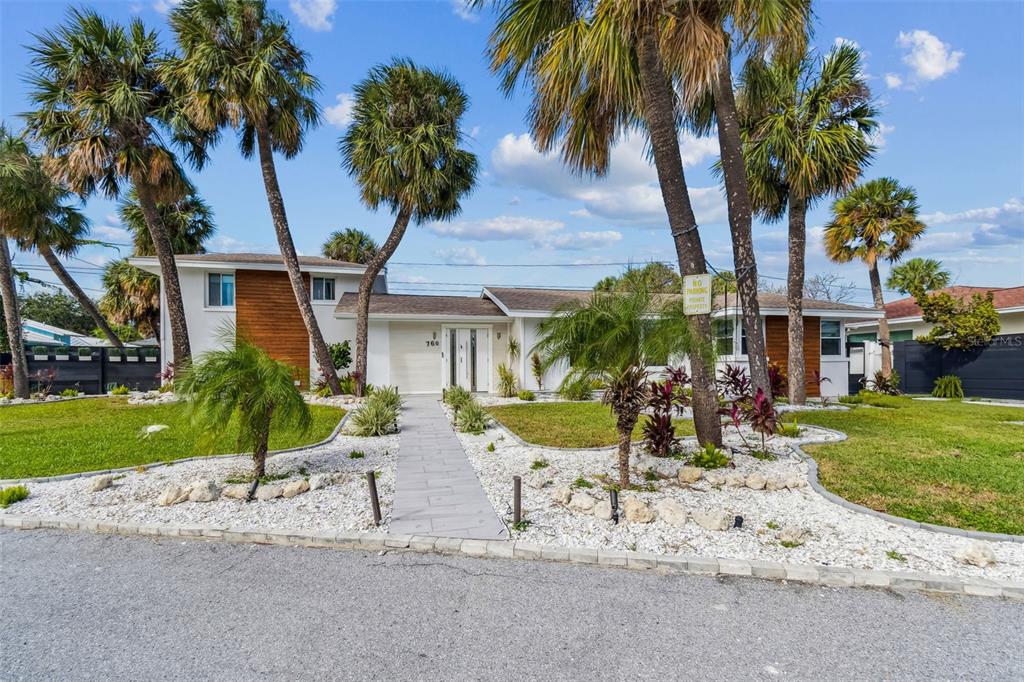 A single-story house with a white exterior, wood accents, and palm trees in the front yard — 760 BOHENIA CIRCLE S, CLEARWATER BEACH, FL