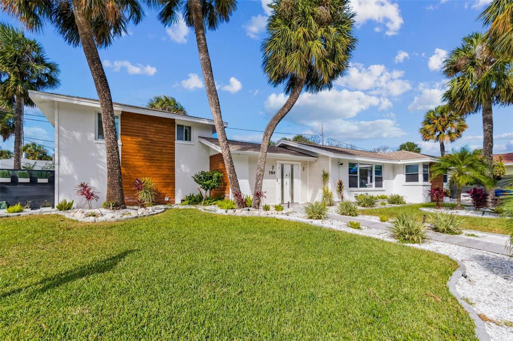 A single-story house with white walls, wood siding, and palm trees in the front yard — 760 BOHENIA CIRCLE S, CLEARWATER BEACH, FL