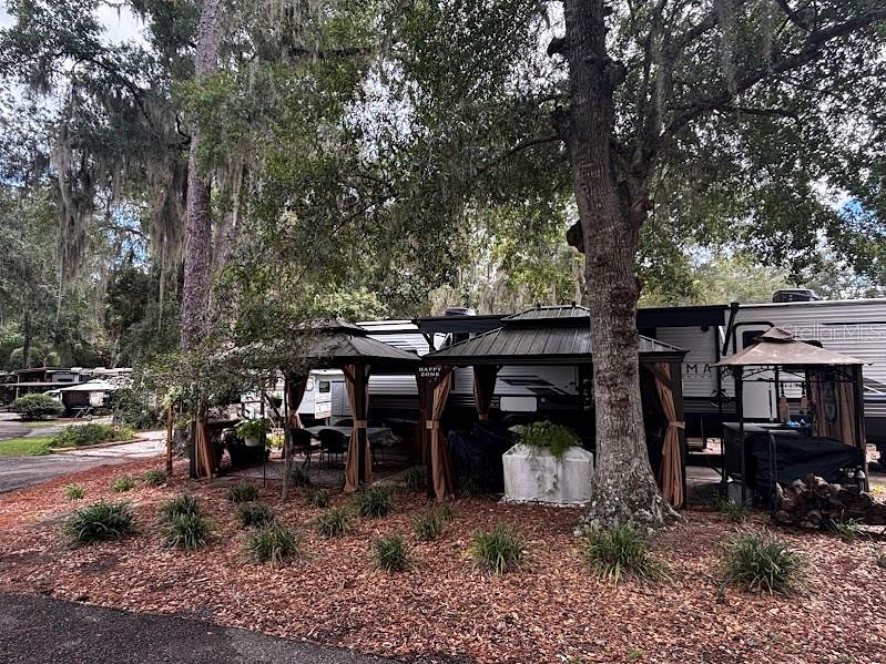 A large recreational vehicle is parked under trees next to two outdoor gazebos — 14105 253RD AVENUE ROAD NE UNIT 392, FORT MC COY, FL