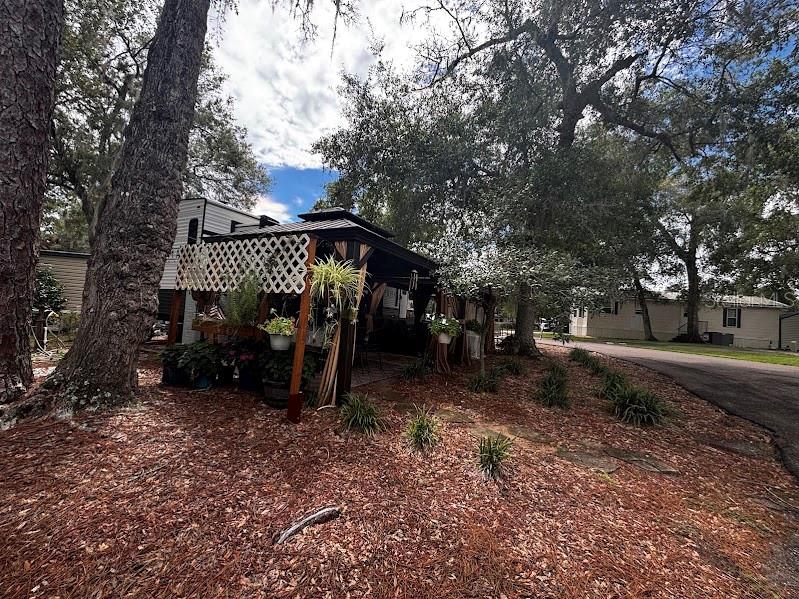 A wooden gazebo with lattice siding sits in a yard covered with pine needles — 14105 253RD AVENUE ROAD NE UNIT 392, FORT MC COY, FL