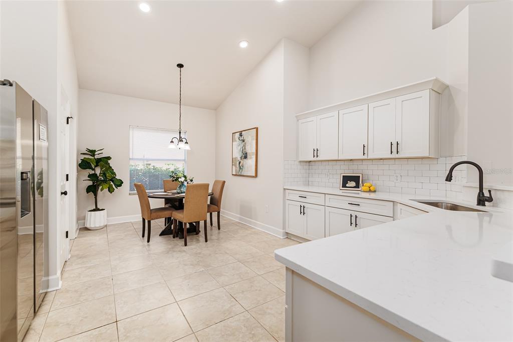 A kitchen and dining area with white cabinets, quartz countertops, and a round wooden table — 1705 ALTAVISTA CIRCLE, LAKELAND, FL
