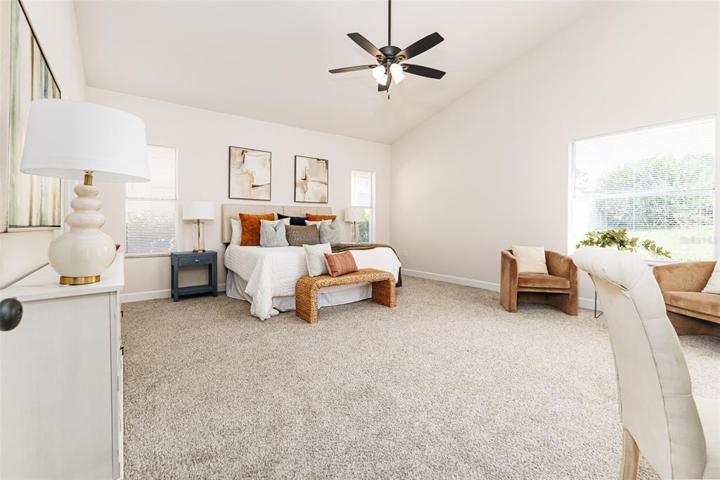 A spacious bedroom features a bed, two armchairs, a ceiling fan, and wall-to-wall carpeting — 1705 ALTAVISTA CIRCLE, LAKELAND, FL