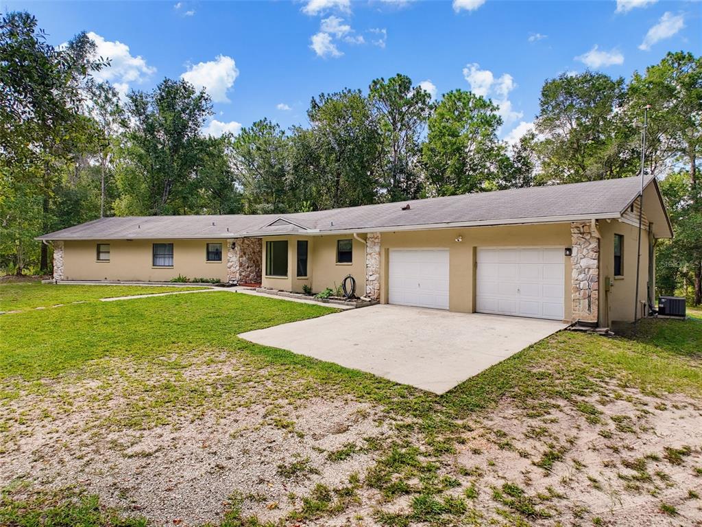 A single-story house with a two-car garage, stone accents, and a large gravel driveway — 26311 WILLOW STREET, BROOKSVILLE, FL