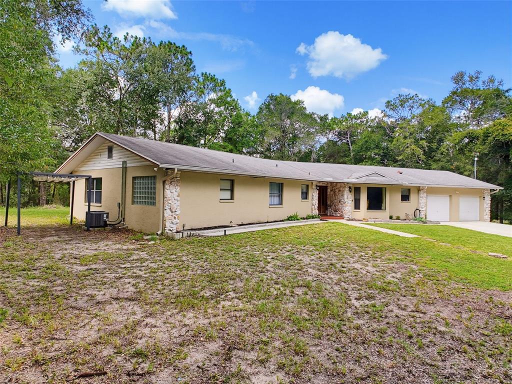 A single-story ranch-style house with a tan exterior, stone accents, and an attached two-car garage — 26311 WILLOW STREET, BROOKSVILLE, FL