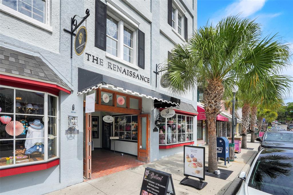 The exterior of a multi-story building features storefronts, signage, and a palm tree on the sidewalk — 411 N DONNELLY ST, MOUNT DORA, FL