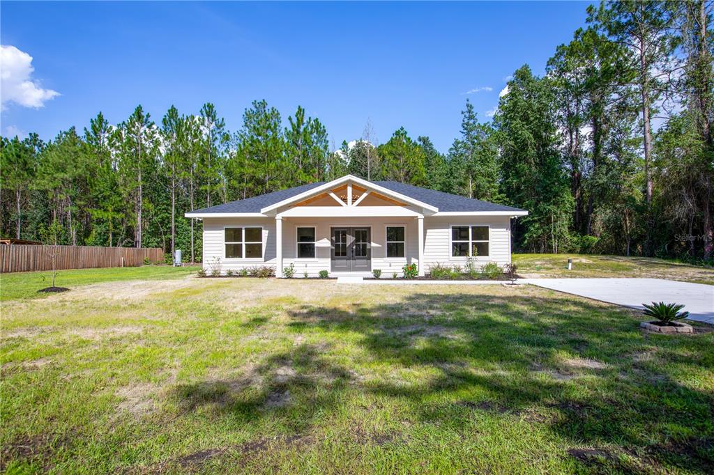 A single-story house with light siding, a gabled porch, and a dark roof sits outdoors — 12856 NE 233RD LANE, RAIFORD, FL