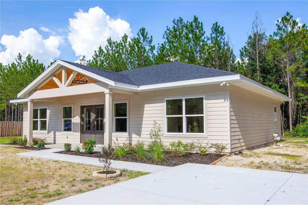 A single-story house with beige horizontal siding, a covered front porch, and a dark roof — 12856 NE 233RD LANE, RAIFORD, FL