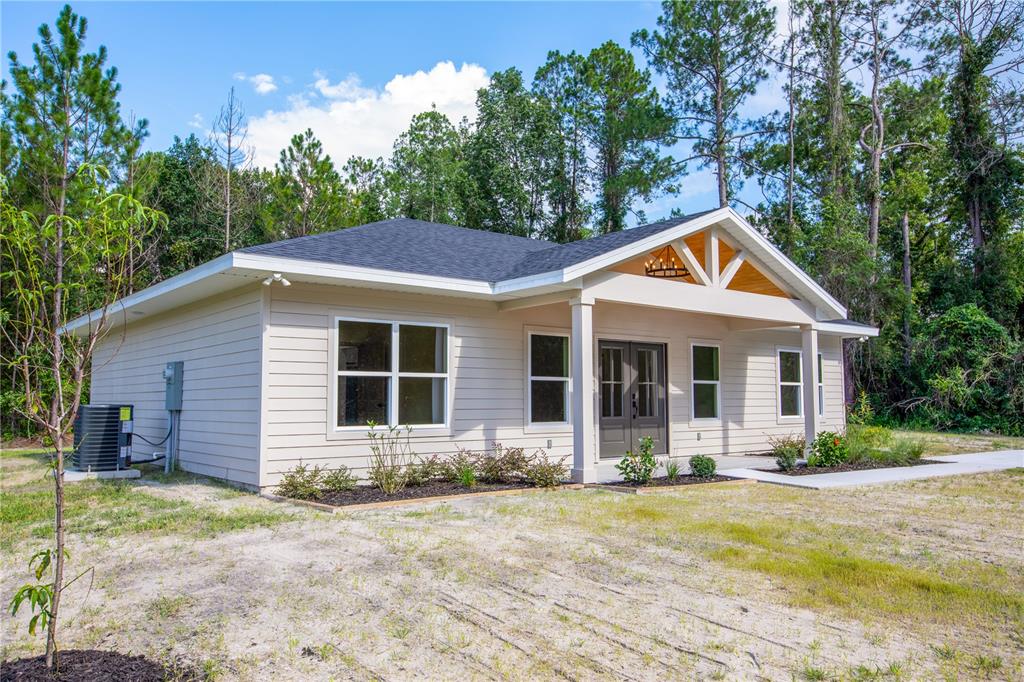 A single-story house with beige siding, a covered front porch, and a dark shingled roof — 12856 NE 233RD LANE, RAIFORD, FL