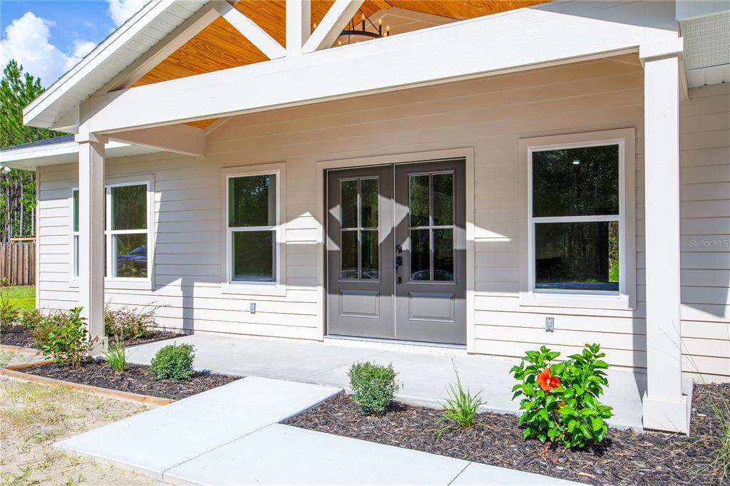 The exterior of a house features a covered porch, double front doors, and light-colored siding — 12856 NE 233RD LANE, RAIFORD, FL
