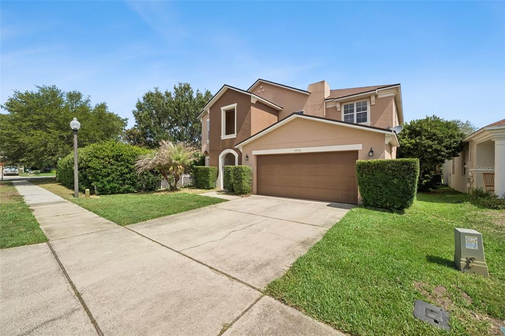 A two-story house with a tan stucco exterior and a two-car garage — 5056 GANDROSS LANE, MOUNT DORA, FL