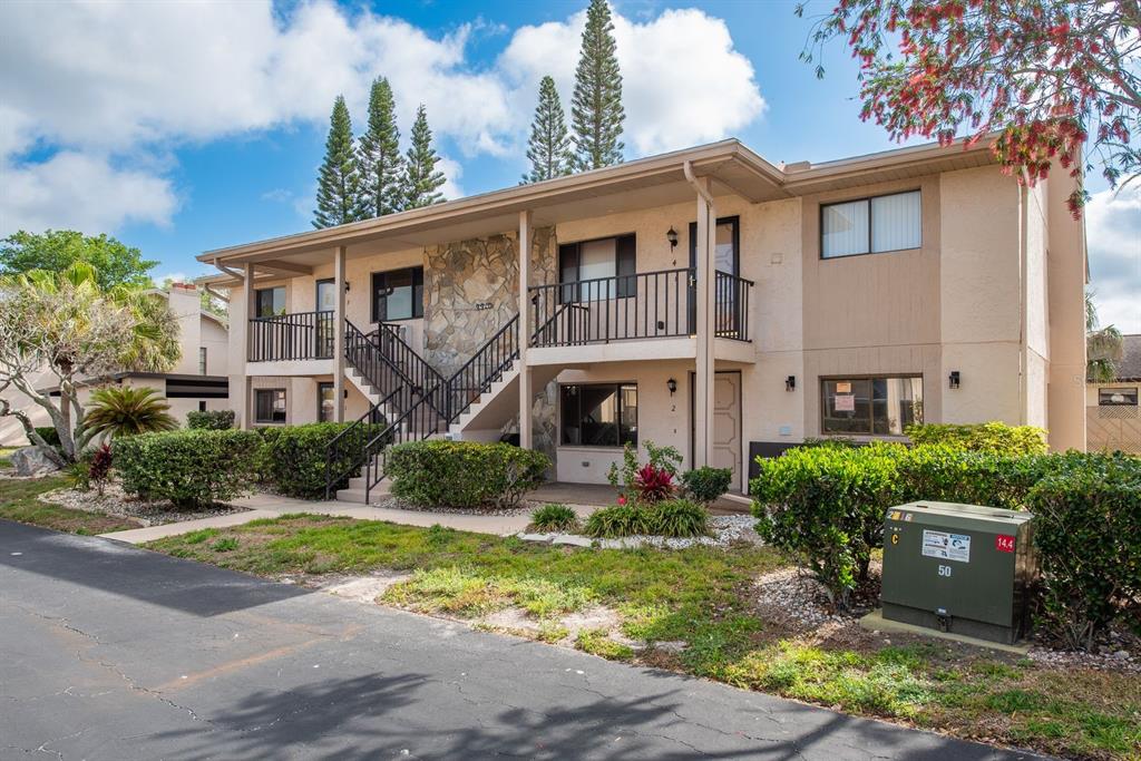 A two-story apartment building with a stone facade, exterior staircase, and metal railings — 9910 EAGLES POINT CIRCLE UNIT 3, PORT RICHEY, FL