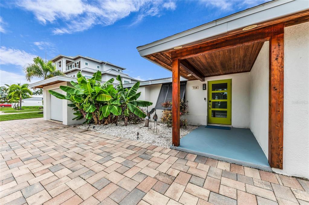 A modern home exterior features a lime green front door, wood-paneled porch ceiling, and pavers — 714 NORTON STREET, LONGBOAT KEY, FL