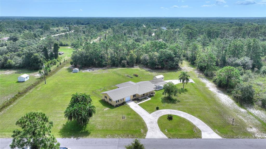 An aerial view shows a single-story house with a circular driveway and surrounding wooded land — 6273 TORONJA DRIVE, INDIAN LAKE ESTATES, FL