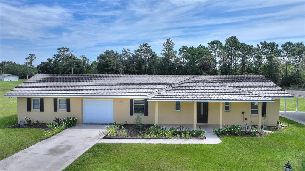 A single-story house with a yellow exterior, a gray shingled roof, and a front porch — 6273 TORONJA DRIVE, INDIAN LAKE ESTATES, FL