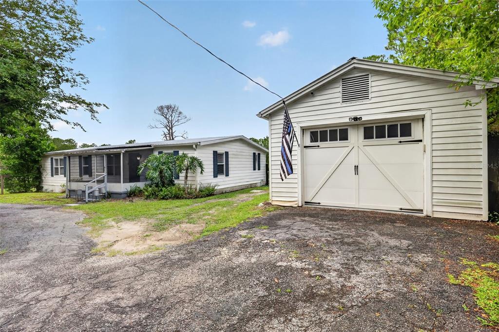 A white detached garage stands next to a single-story house with a screened porch — 32439 HIGHLAND LAKES ROAD, DELAND, FL