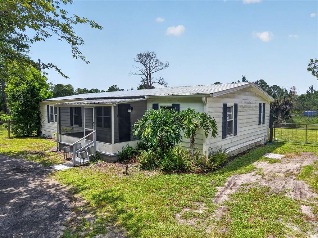 A single-story mobile home with a screened-in front porch sits on a grassy lot — 32439 HIGHLAND LAKES ROAD, DELAND, FL