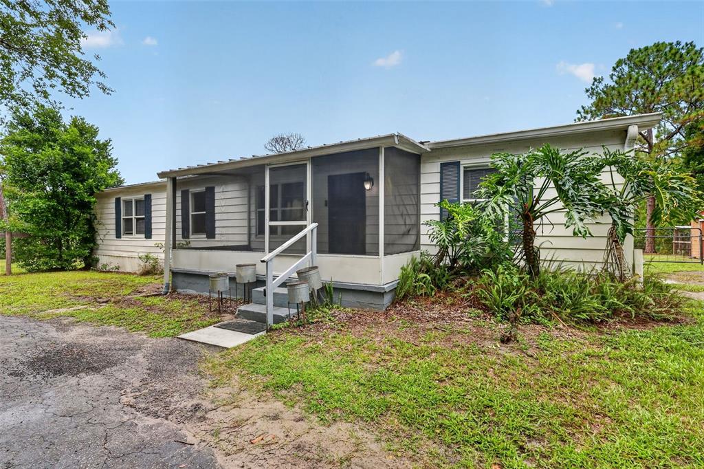 A single-story house with white siding, a screened-in porch, and a gravel driveway — 32439 HIGHLAND LAKES ROAD, DELAND, FL