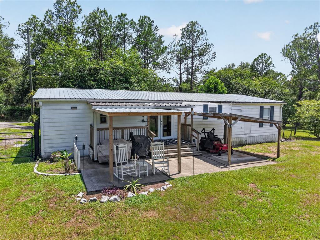 A single-story manufactured home features a metal roof, a covered patio, and a lawn — 32439 HIGHLAND LAKES ROAD, DELAND, FL