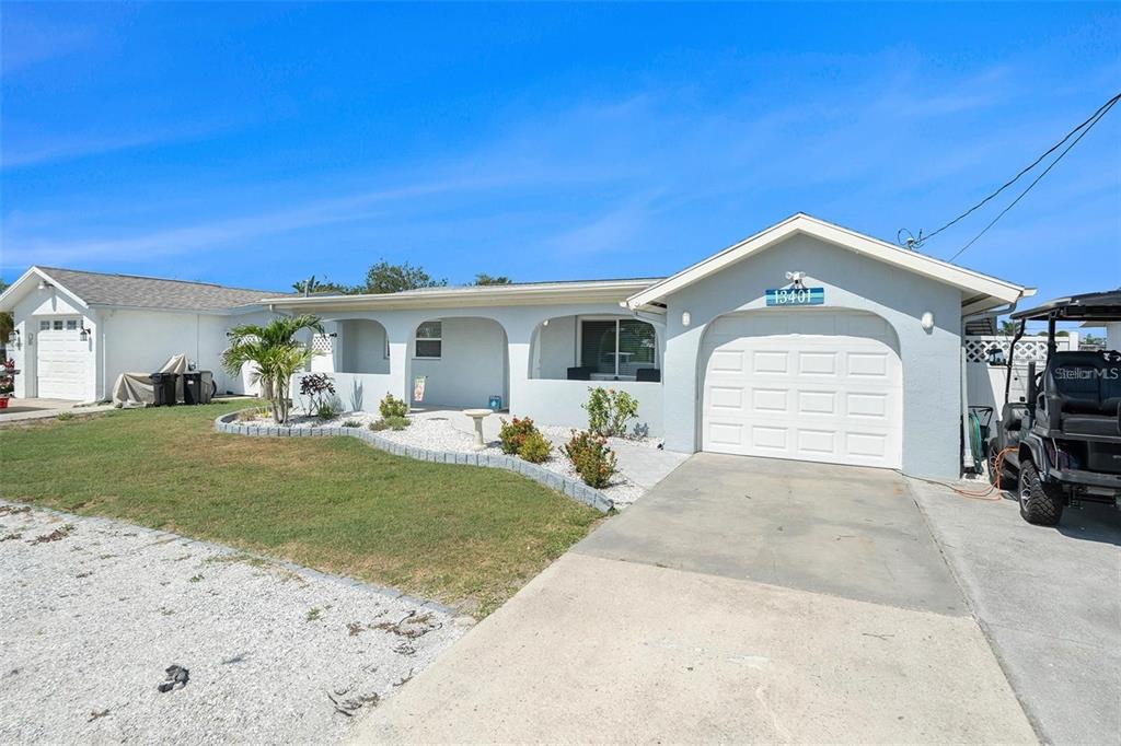 A single-story house with a white exterior, a garage, and a front porch — 13401 NEPTUNE DRIVE, HUDSON, FL