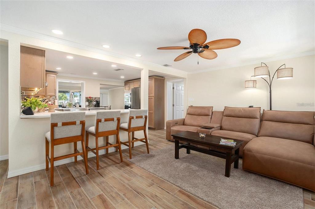 An open-concept living room and kitchen featuring a brown sectional sofa and breakfast bar seating — 13401 NEPTUNE DRIVE, HUDSON, FL