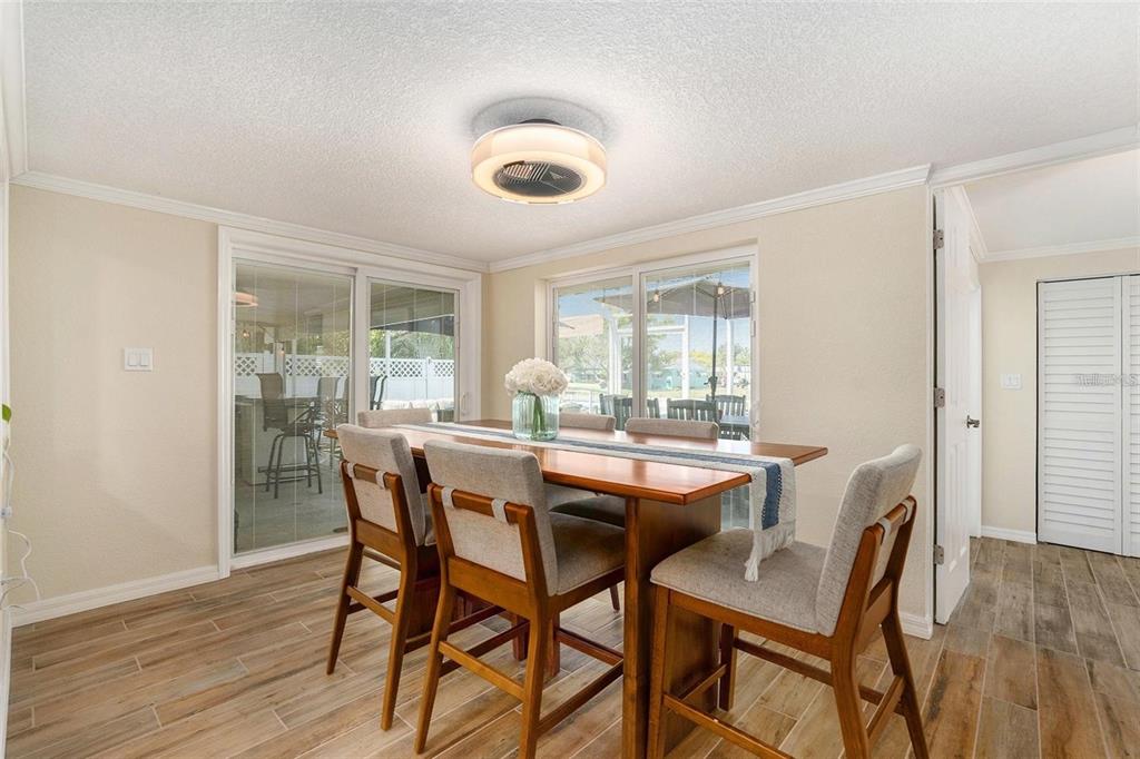 A dining room with a wooden table, upholstered chairs, tile flooring, and a ceiling fan light — 13401 NEPTUNE DRIVE, HUDSON, FL