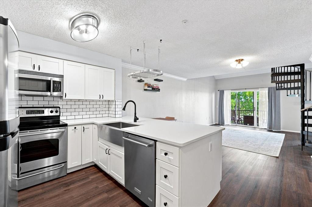 A modern kitchen with white cabinets, stainless steel appliances, and a spiral staircase nearby — 2400 FEATHER SOUND DRIVE UNIT 133, CLEARWATER, FL
