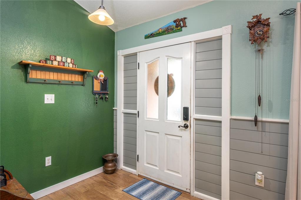 An entryway features a green wall, a white front door with sidelights, and wood flooring — 1755 BETH LANE, WINTER HAVEN, FL