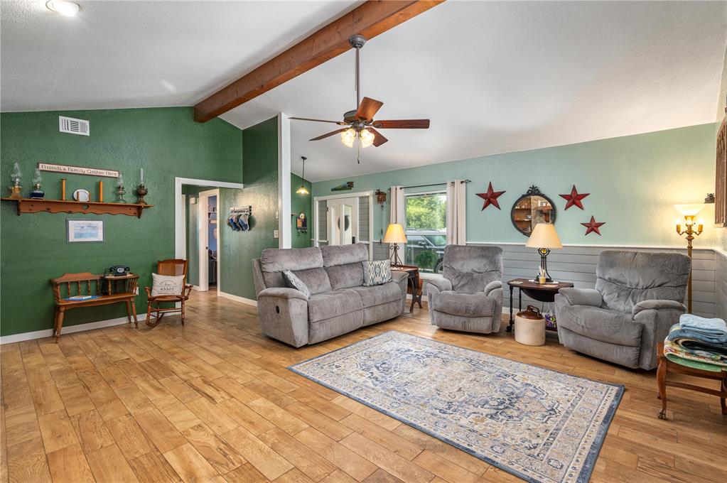 A living room with wood-look tile floors, a vaulted ceiling, and a wooden beam — 1755 BETH LANE, WINTER HAVEN, FL