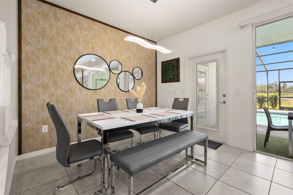 A dining room features a marble-topped table, gray chairs, a bench, and a textured wall — 7127 OAKMOSS LOOP, DAVENPORT, FL