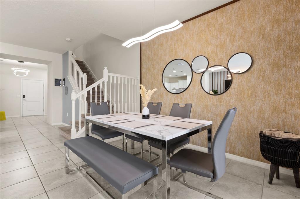 A dining room features a marble-top table, grey chairs, a bench, and circular wall mirrors — 7127 OAKMOSS LOOP, DAVENPORT, FL