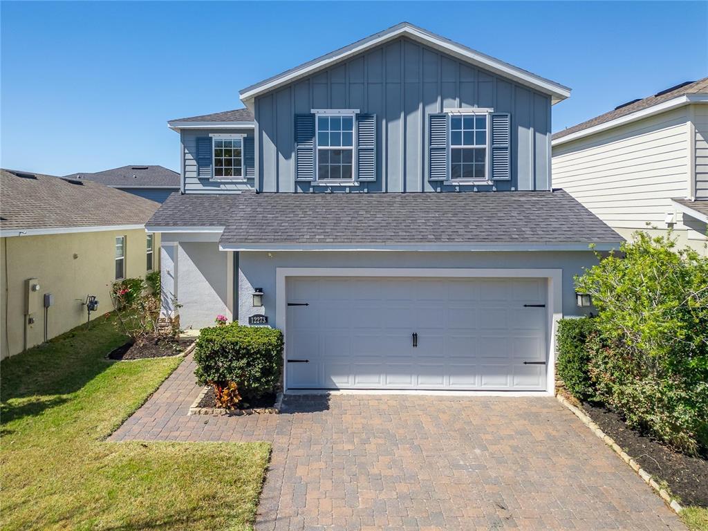 A two-story house with blue vertical siding, a gray garage door, and a paver driveway — 12273 BLUE PACIFIC DRIVE, RIVERVIEW, FL