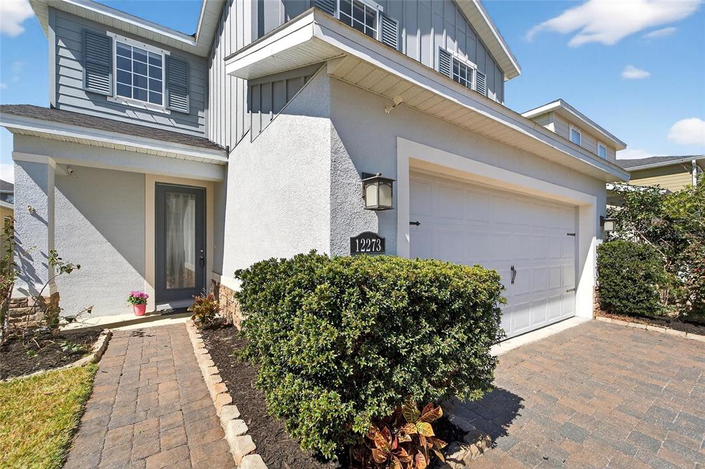A two-story house exterior features a white stucco facade, a garage, and a brick walkway — 12273 BLUE PACIFIC DRIVE, RIVERVIEW, FL