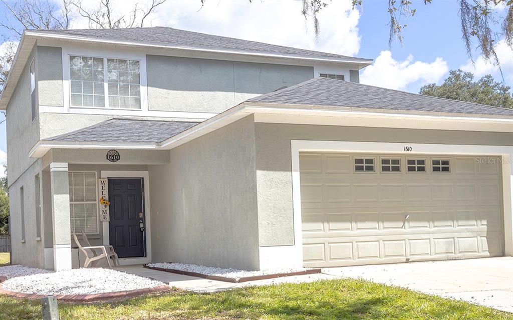 A two-story house with a light-colored stucco exterior, a dark front door, and a two-car garage — 1610 MARSH WOOD DRIVE, SEFFNER, FL