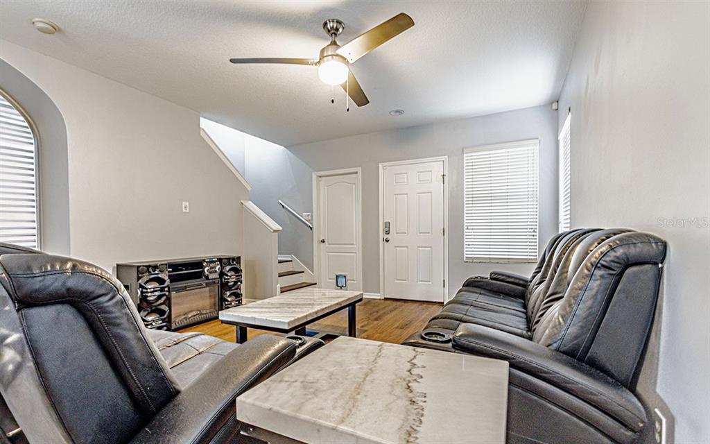 A living room features a ceiling fan, leather sofas, a coffee table, and a staircase — 1610 MARSH WOOD DRIVE, SEFFNER, FL