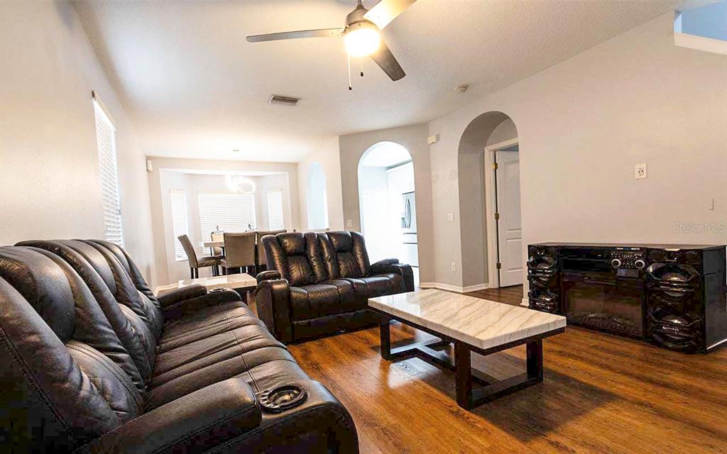 A living room with dark leather furniture, a marble-topped coffee table, and wood-look flooring — 1610 MARSH WOOD DRIVE, SEFFNER, FL