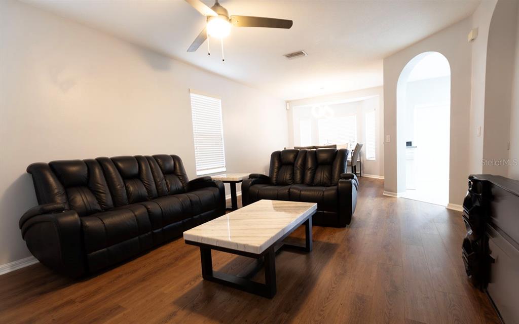 A living room features dark leather sofas, a marble coffee table, and wood-look flooring — 1610 MARSH WOOD DRIVE, SEFFNER, FL