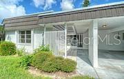 A white single-story home features a dark shingled roof, a carport, and a front patio — 3961 ASHWOOD LANE UNIT 44, SARASOTA, FL