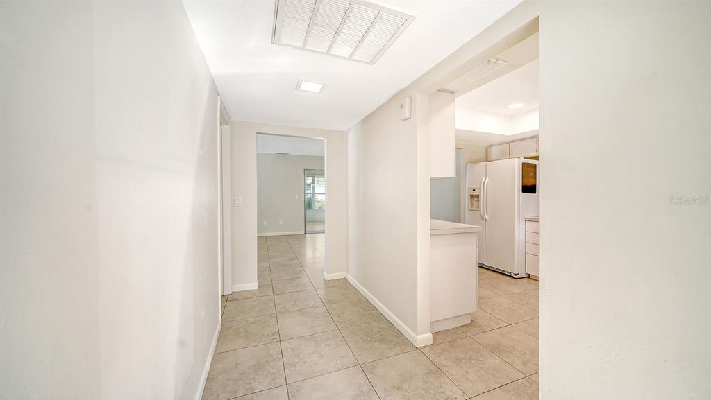 A tiled hallway leads to a kitchen with a white refrigerator and an adjacent room — 3961 ASHWOOD LANE UNIT 44, SARASOTA, FL
