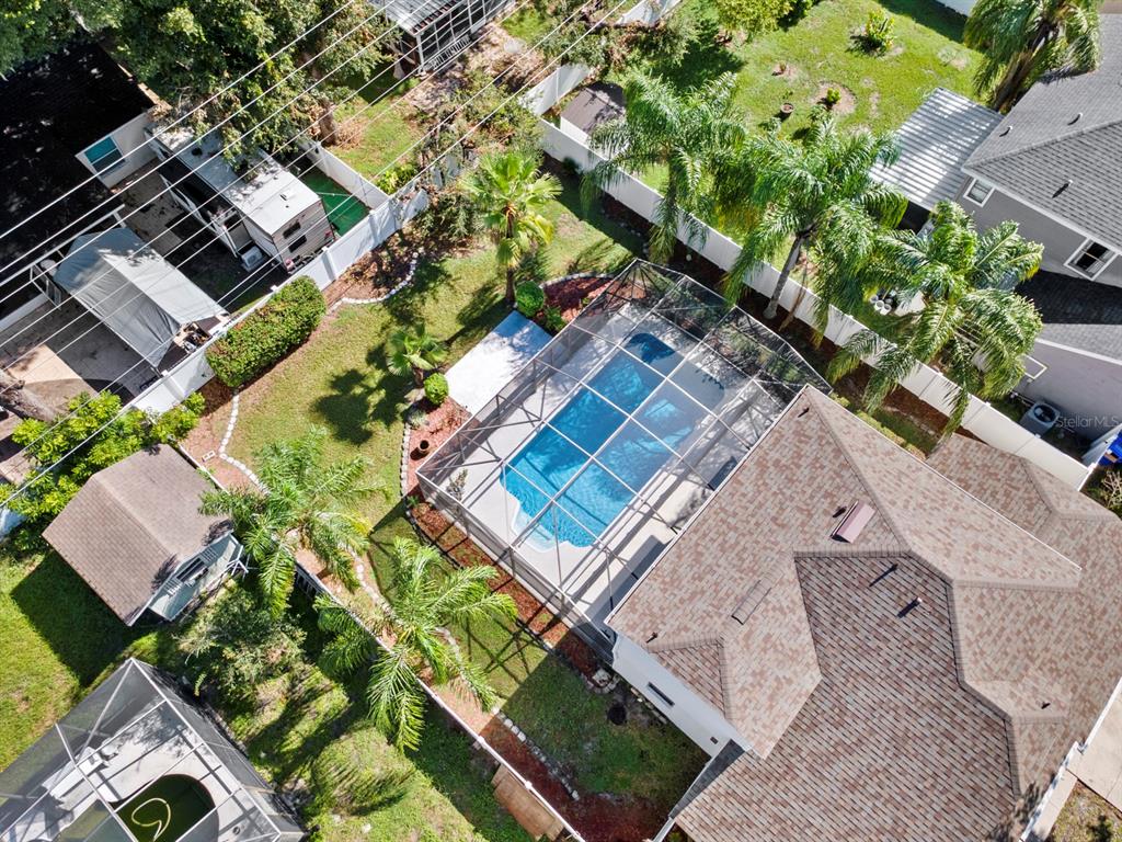 An aerial view shows a house with a screened-in pool, palm trees, and a backyard — 1461 AMANDA ROAD, KISSIMMEE, FL